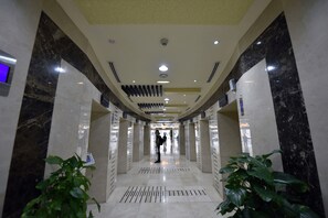 Enter a beautifully designed lobby with a central walkway, marble walls, and recessed lighting.