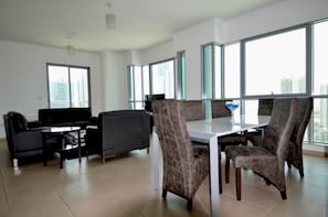 A modern living room with a large window, a dining table, and comfortable seating.