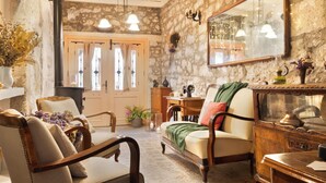 A cozy room with a stone wall, a wooden cabinet, a mirror, and a sofa. - Krem Hotel (Cesme)