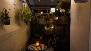 A cozy indoor space with hanging plants, a small round table, and a chair. - Urban Hive Backpackers (Cape Town)