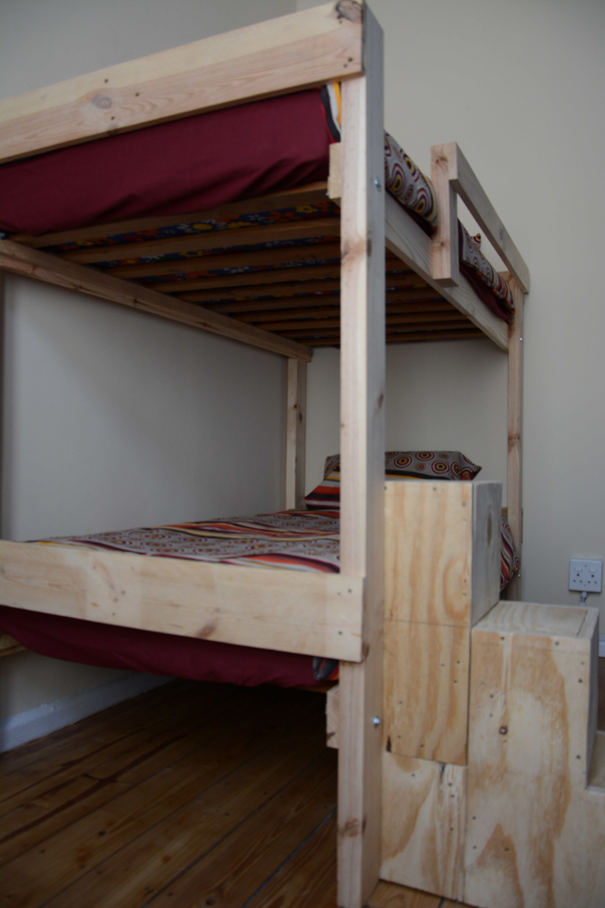 Un letto a castello con struttura in legno e copripiumone rosso.
