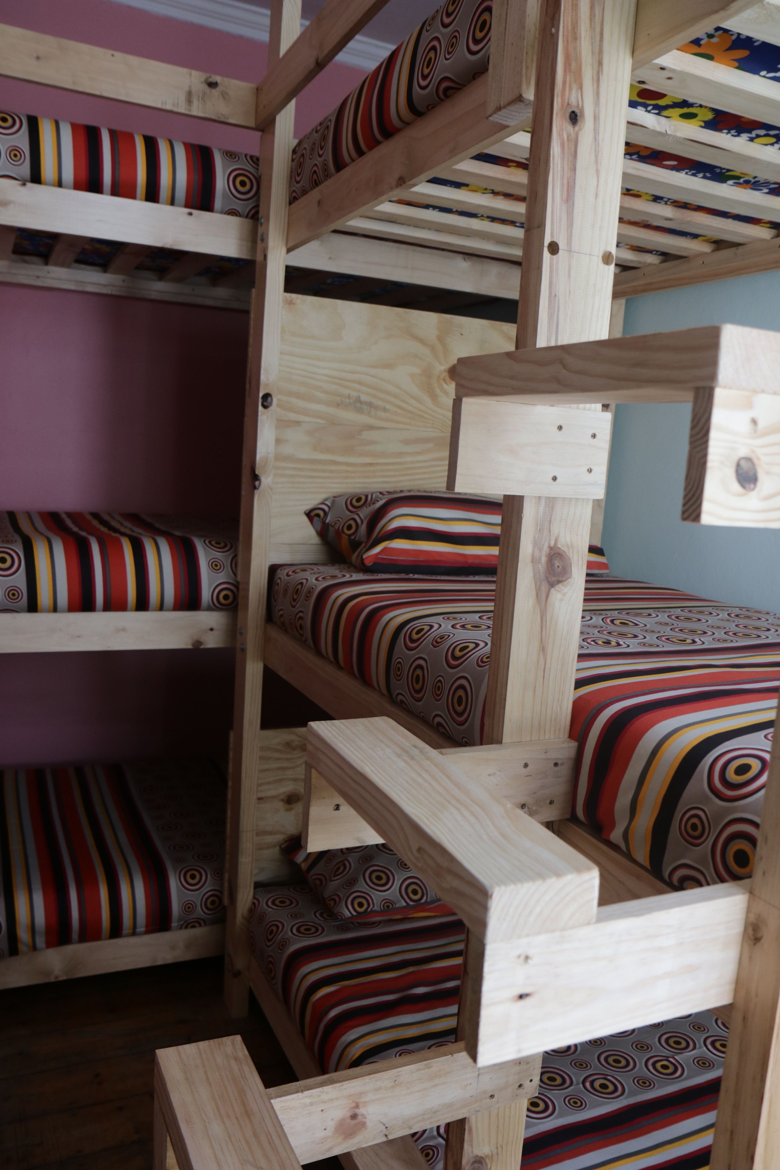 A bunk bed with multiple levels, each with a colorful striped bedspread.