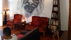 A living room with a mural, a bookshelf, and a red sofa. - Urban Hive Backpackers (Cape Town)
