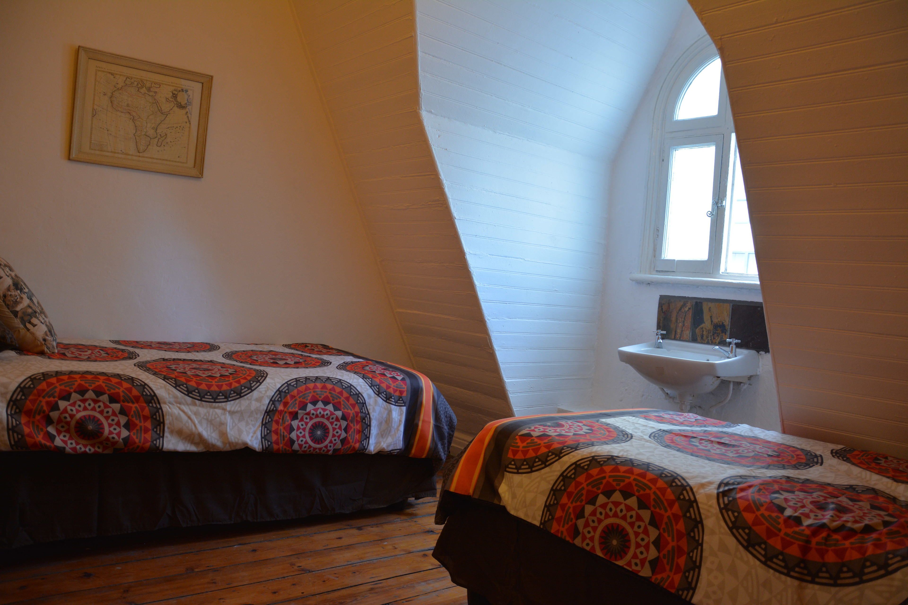 A bedroom with two beds, a window, and a small white sink.