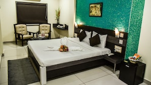 Habitación de hotel con una cama, dos sillones, una mesita, una mesita de noche y un aire acondicionado instalado en la pared.