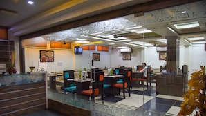 Un restaurante moderno con divisiones de vidrio, mostrador de recepción de madera y sillas coloridas.