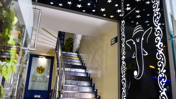 Fachada de hotel con una escalera que conduce a los pisos superiores, un letrero que indica un restaurante y decoración en la pared.