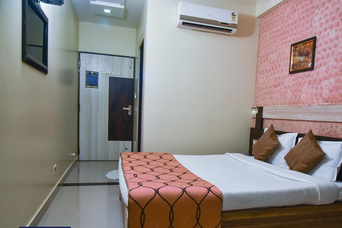 Una habitación de hotel con una cama, una mesita de noche, un cuadro en la pared y un equipo de aire acondicionado.