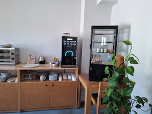 Eine Küchenzeile mit Kaffeemaschine, einem kleinen Kühlschrank und einem Blumentopf.