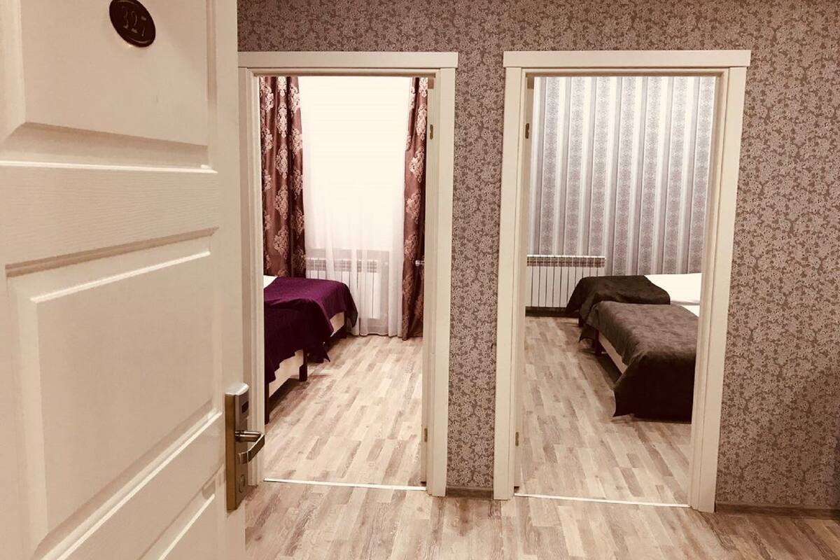 Una habitación con dos camas, una puerta con placa de número y una pared con diseño.