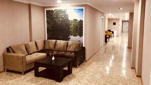 Un moderno vestíbulo de hotel con un sofá color beige, una mesa de centro y un cartel grande de un paisaje natural.