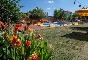 Una piscina al aire libre, sombrillas, sillones reclinables de piscina