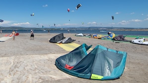 Une plage où l’on voit de nombreux cerfs-volants et une personne en maillot de bain.