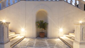 A stone staircase leading to an arched doorway with a potted plant. - Vistaterra (Parella)