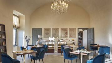 Un coin repas avec des chaises bleues, un lustre et une table dressée avec des assiettes et des verres.