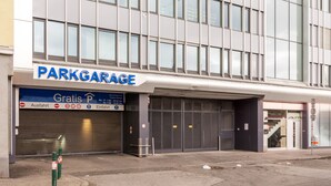 A building with a sign reading "PARKGARAGE" and a blue sign below it indicating free parking hours. - Senator Flats (Vienna)