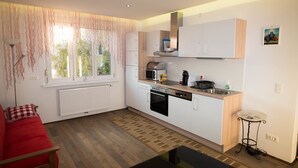 A compact kitchen with white cabinets, a built-in oven, and a coffee maker. - Senator Flats (Vienna)