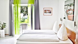 Ein Hotelzimmer mit einem Bett, einer Zimmerpflanze und Blick ins Freie.