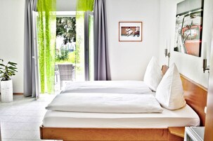 Habitación de hotel con cama, una planta en maceta y vistas al exterior.