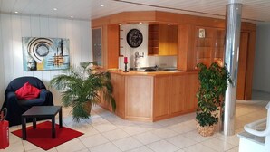 Eine moderne Lobby mit einem Holzbüro, einem großen abstrakten Gemälde und einer Topfpflanze.