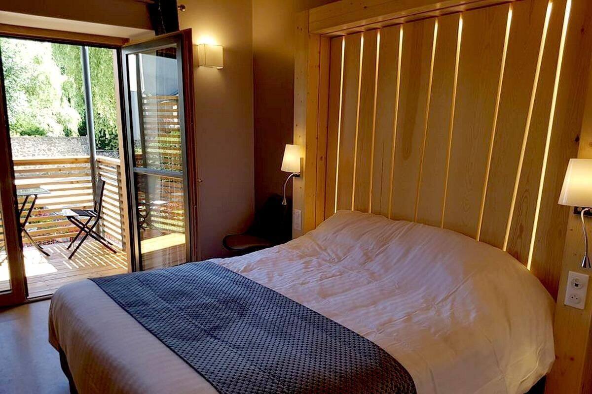 A bedroom with a bed, a sliding glass door leading to an outdoor area, and a wooden wall.