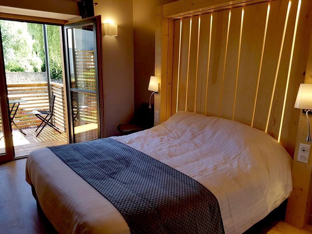Une chambre avec un lit, une porte-fenêtre coulissante donnant sur un espace extérieur et un mur en bois.