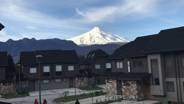 A residential area with modern houses, a street, and a snow-capped mountain in the background. - Condominio Costa Pucon (Pucón)
