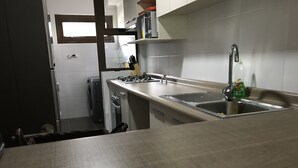 A kitchen with a stainless steel countertop, a sink, and a window above the sink. - Condominio Costa Pucon (Pucón)