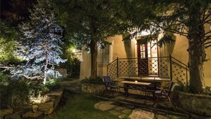 Ein gut beleuchteter Außenbereich mit einer Terrasse, Steintreppen, einem Holztisch und Stühlen.