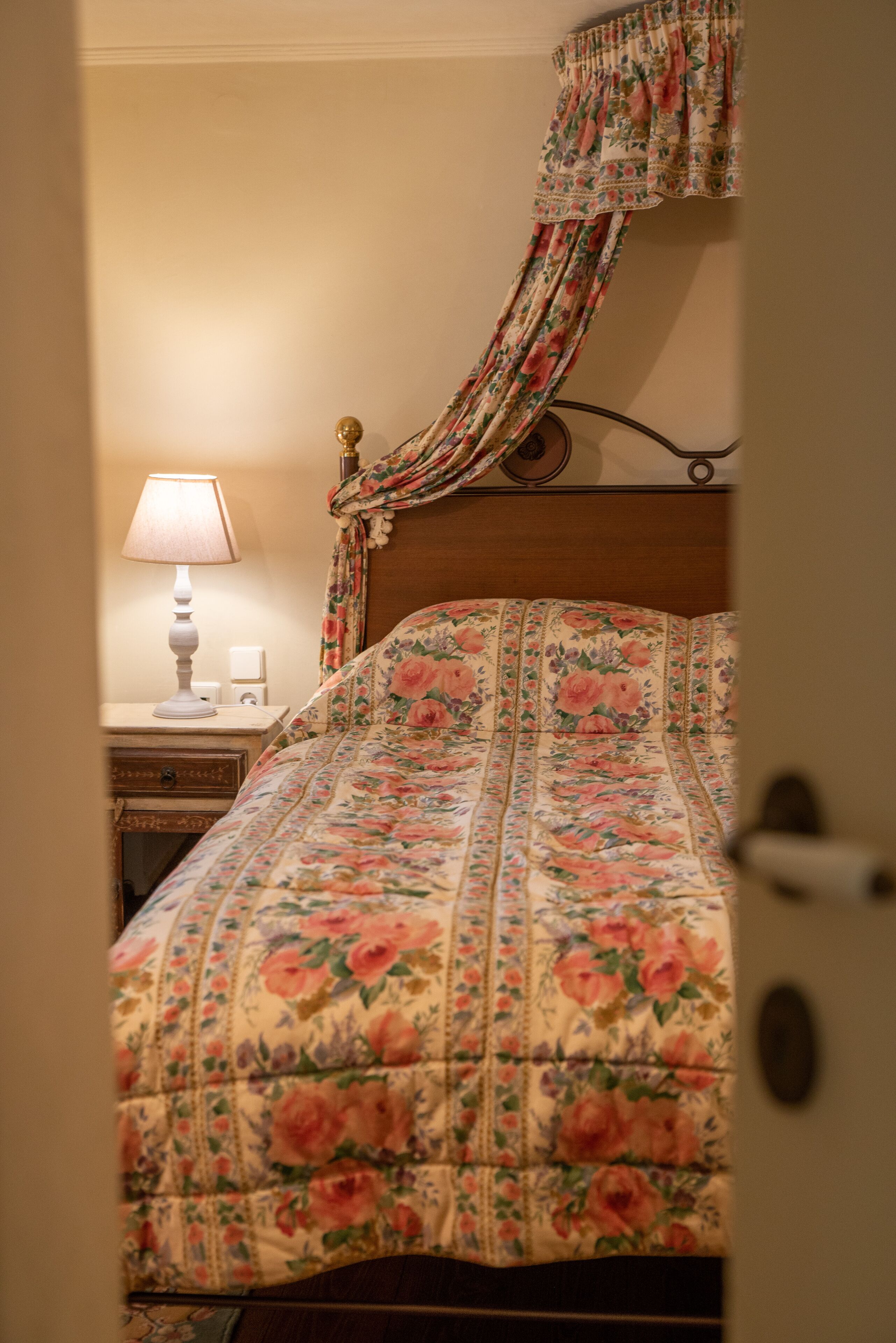 Un dormitorio con colcha estampada, lámpara de noche y cabecero de madera.