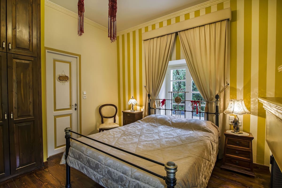 Un dormitorio con cama, armario de madera, mesitas de noche y ventana con cortinas.