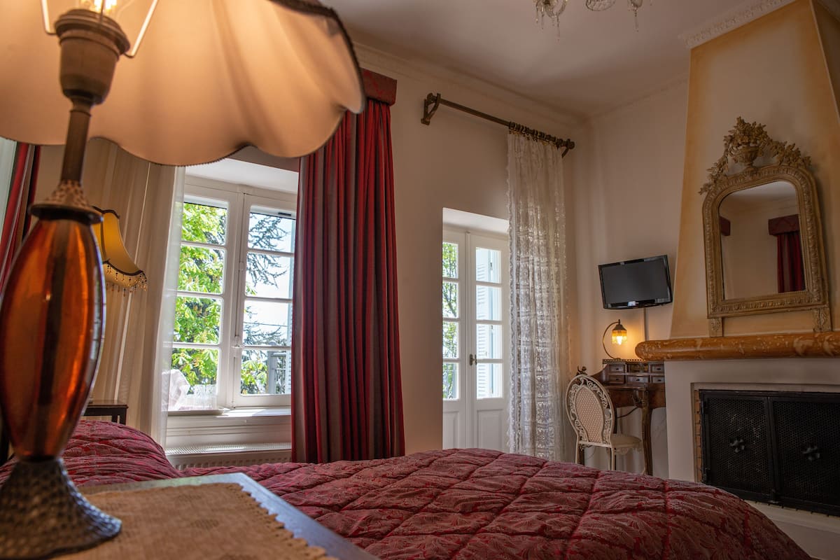 Un dormitorio con cama, televisión, chimenea y ventana con cortinas.