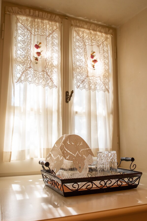 A window with lace curtains and a tray with glasses and a glass pitcher.