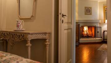 Una habitación con cama, chimenea, espejo y una puerta que da a otra estancia.