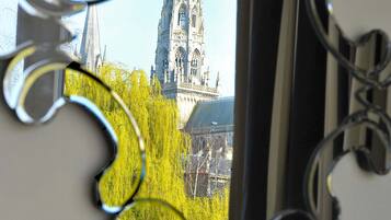 A window with a view of a cathedral and trees.