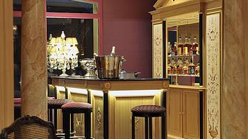 Zona de bar con una columna de mármol, un candelabro y una barra con taburetes.