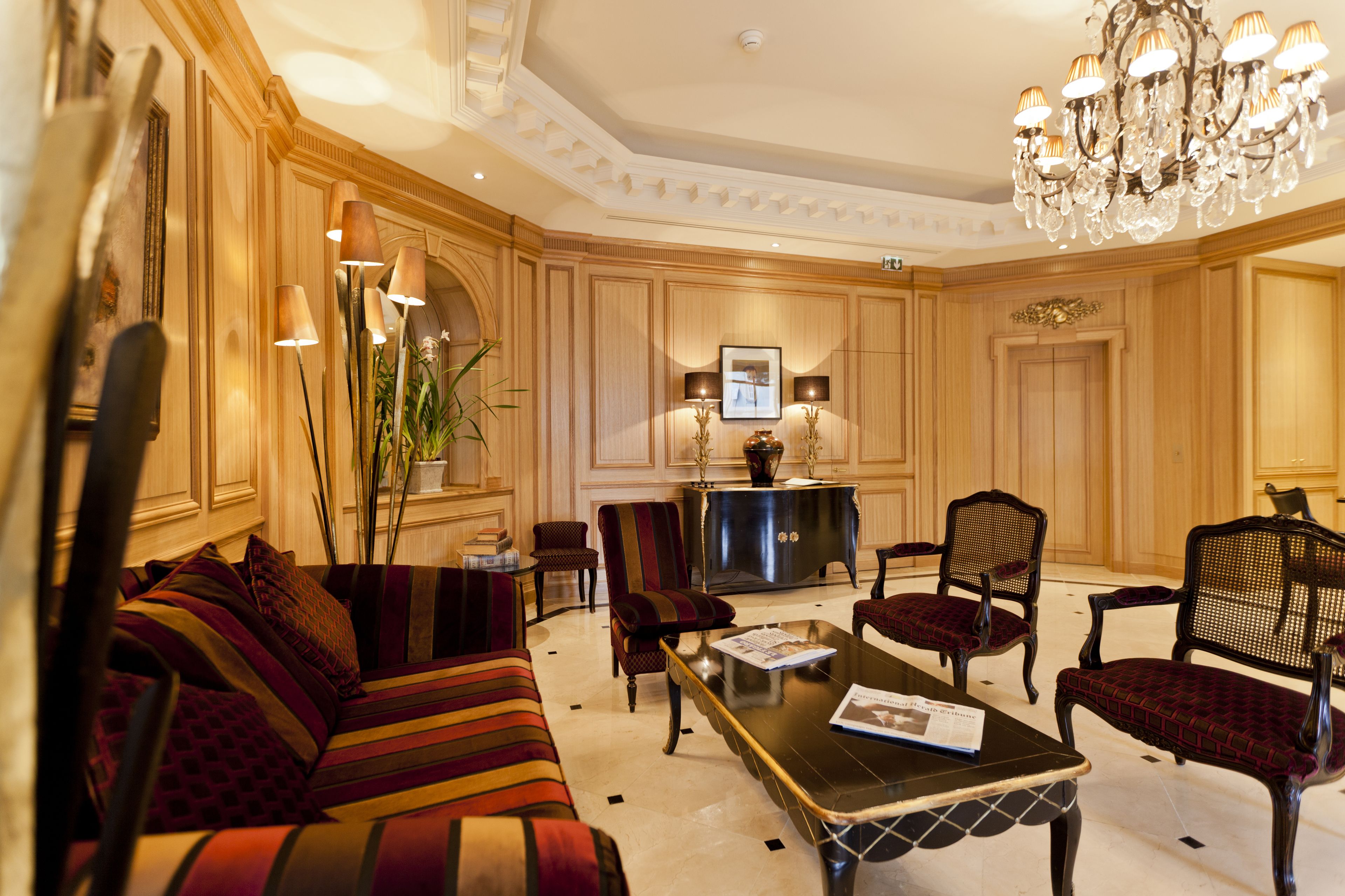A spacious lobby with a large sofa, armchairs, a coffee table, and a chandelier.