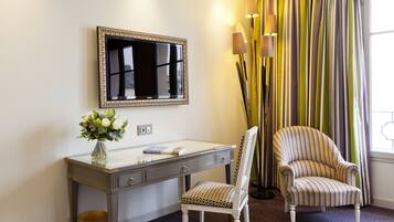A hotel room with a desk, chair, and a large mirror.
