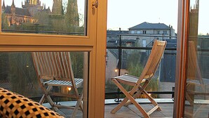 A room with a large window, a patterned armchair, and a wooden chair. - Villa Lara Hôtel (Bayeux)