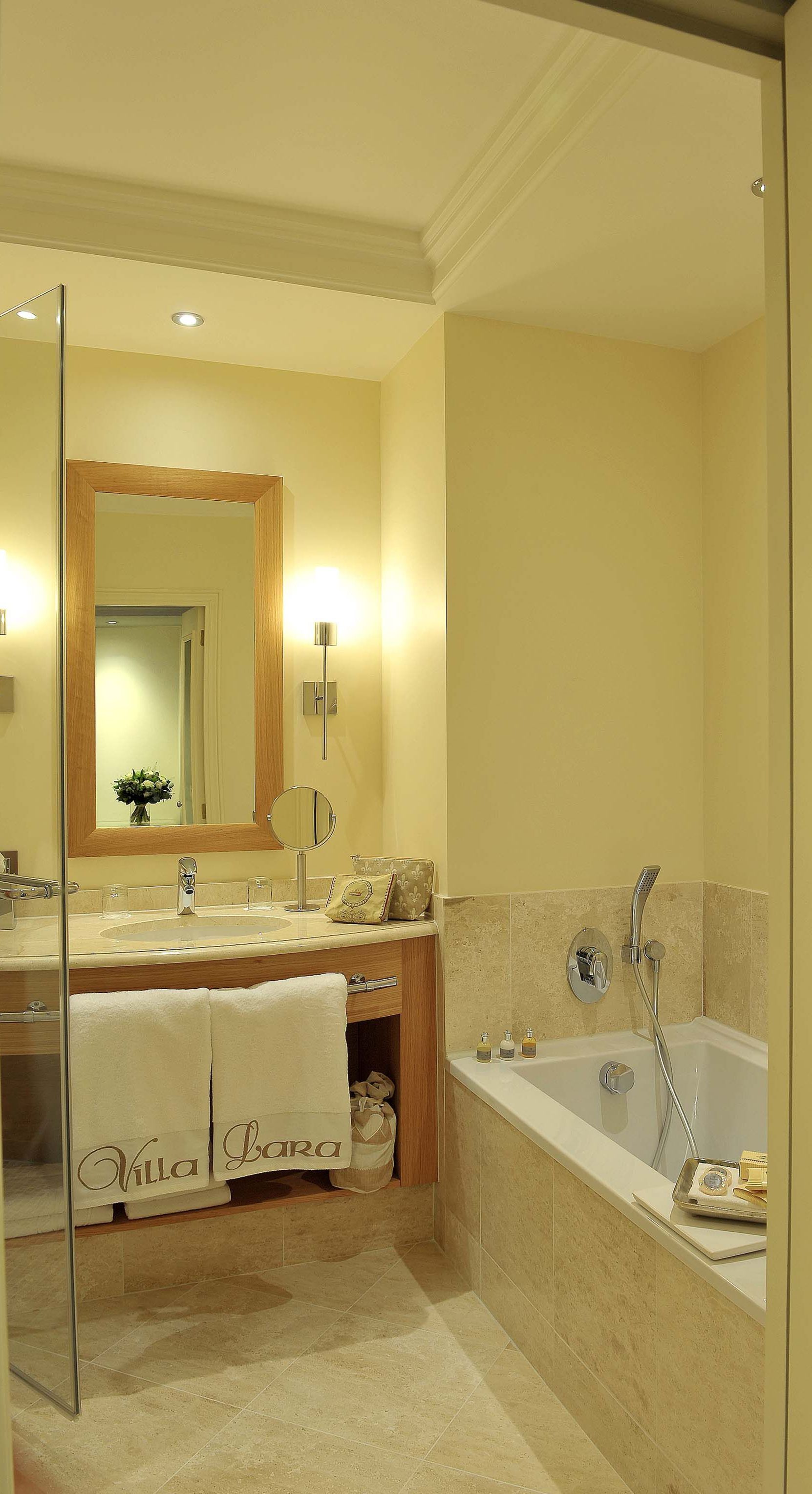 A modern bathroom with a large mirror, a bathtub, and a vanity with a sink and towel rack.