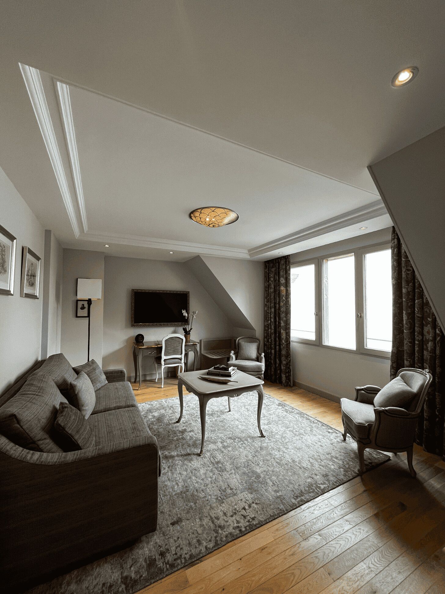 A modern living room with a grey sofa, a coffee table, and a TV mounted on the wall.