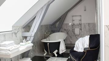 Un baño moderno con piso a cuadros, una bañera, un lavamanos y una silla.