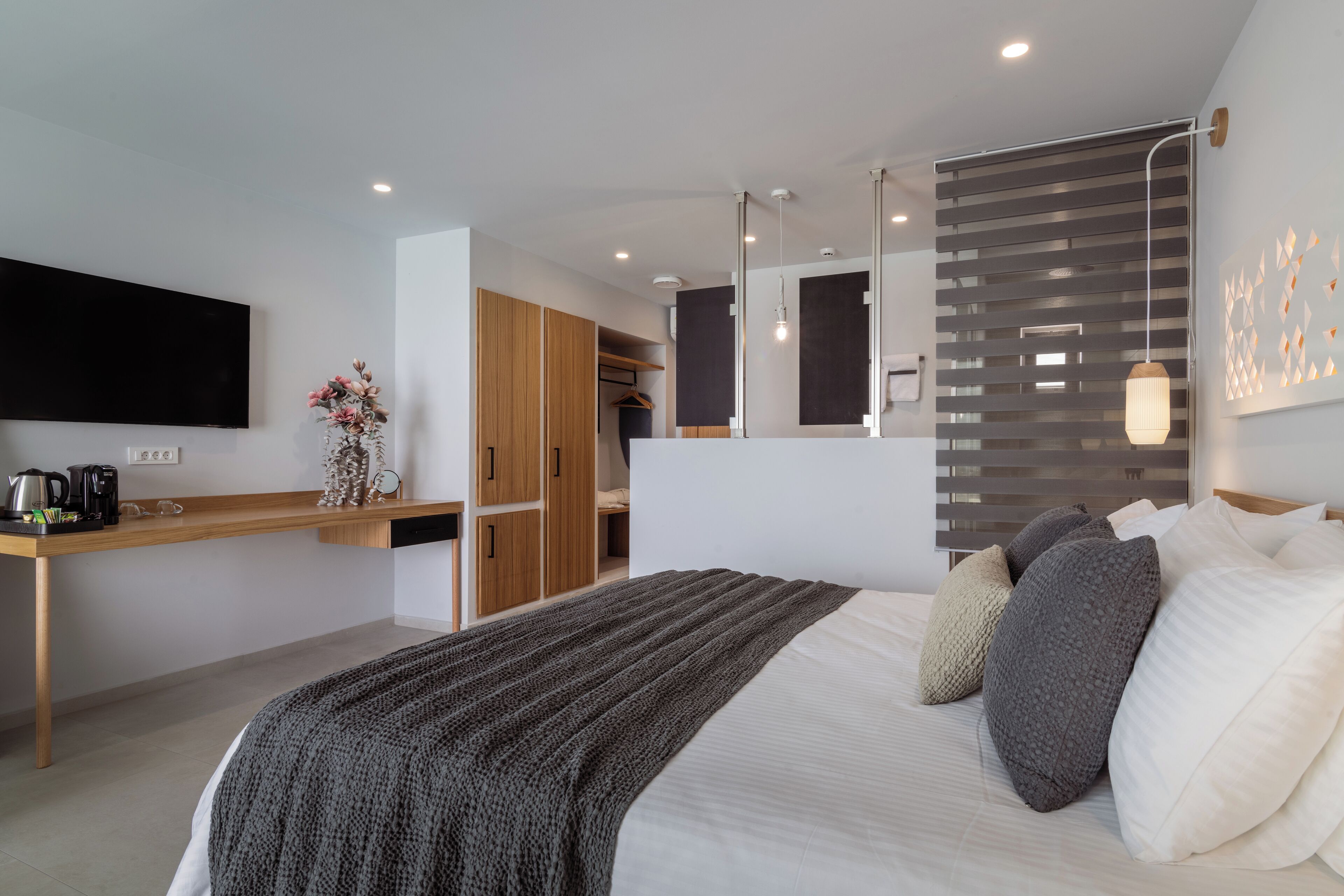 A modern bedroom with a large bed, bedside table, and a built-in wardrobe.