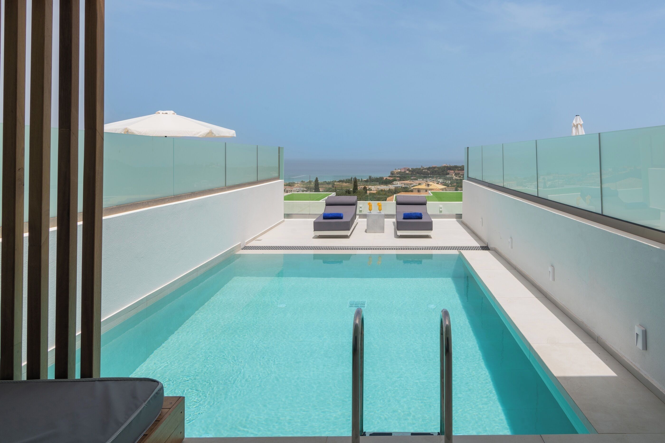 Piscina en la azotea con dos sillones de descanso y vistas al mar.