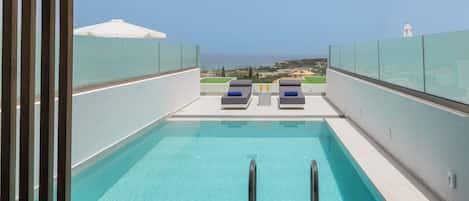 Piscina en la azotea con dos sillones de descanso y vistas al mar.
