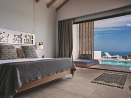 Una camera da letto moderna con un ampio letto, vista sull'oceano e area piscina.