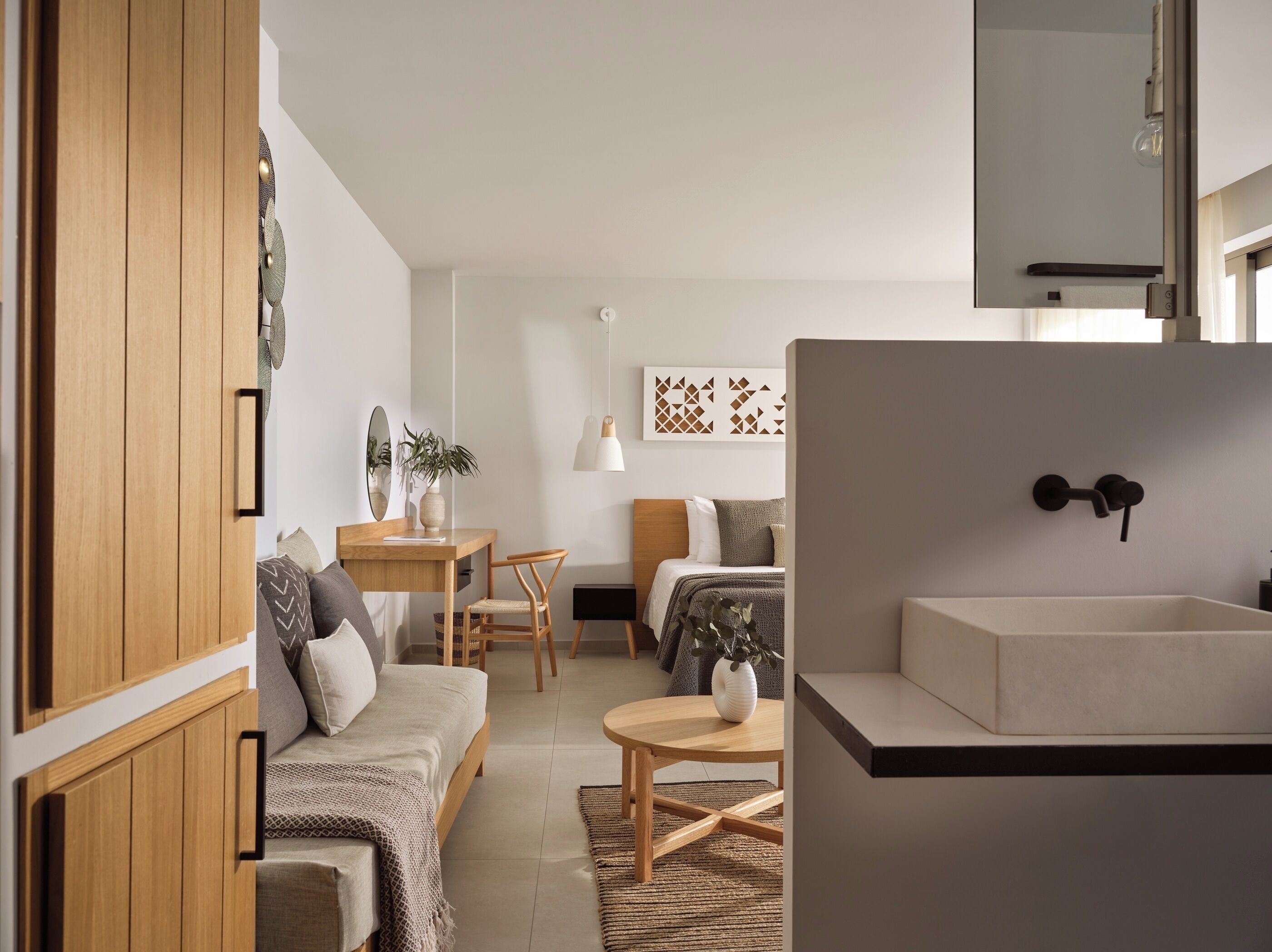 A modern, compact living space with a kitchenette, a bed, a desk, and a dining area.