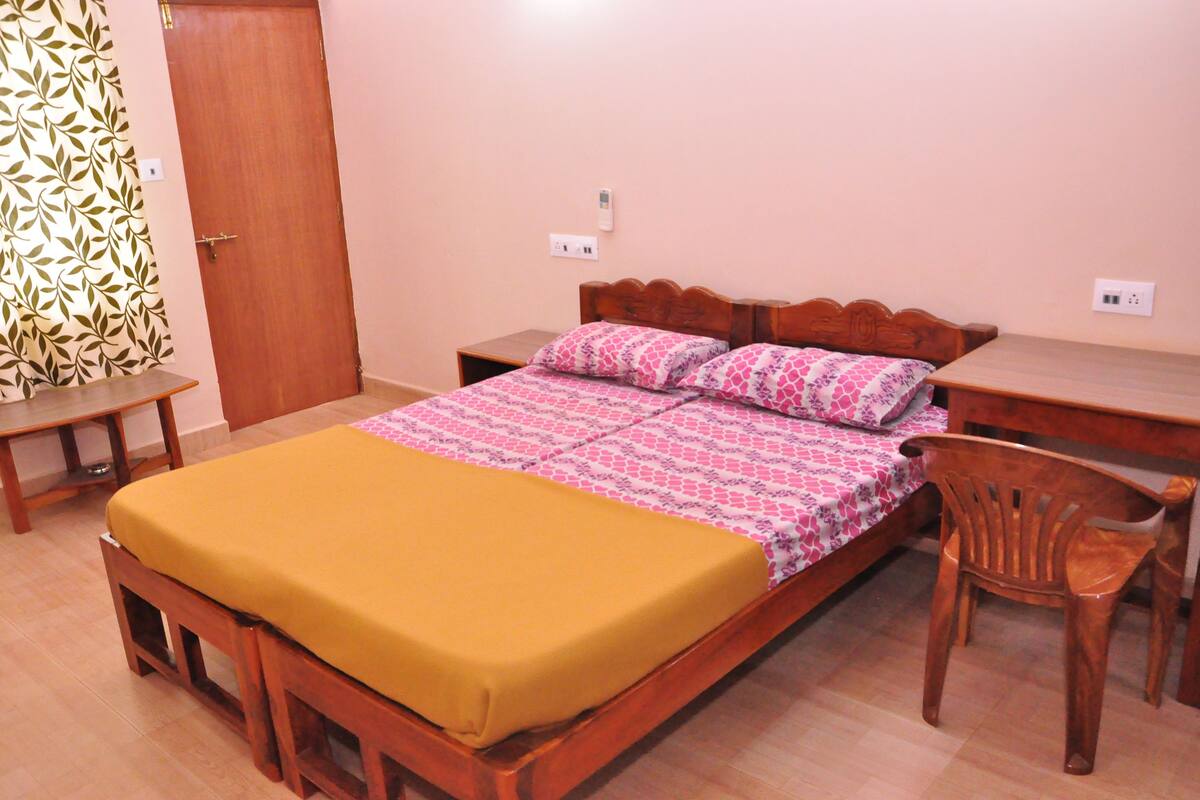 A bedroom with a wooden bed, a bedside table, a chair, and a wardrobe.