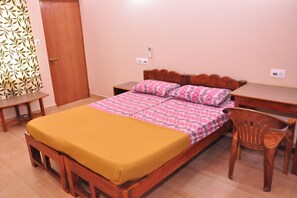 A bedroom with a wooden bed, a bedside table, a chair, and a wardrobe. - Anjuna Blue Resort (Anjuna)