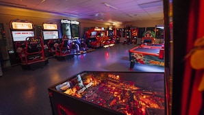 An arcade with multiple gaming machines, including racing and fighting games, in a well-lit indoor setting. - Idre Fjäll Stugor och Lägenheter (Idre)